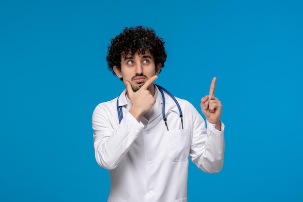 Doctors day curly handsome cute guy in medical uniform thinking and looking up