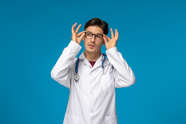 Doctors day handsome brunette cute guy in medical gown holding glasses