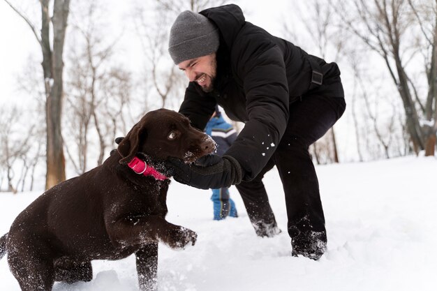 Dog playing with kid in the snow with family