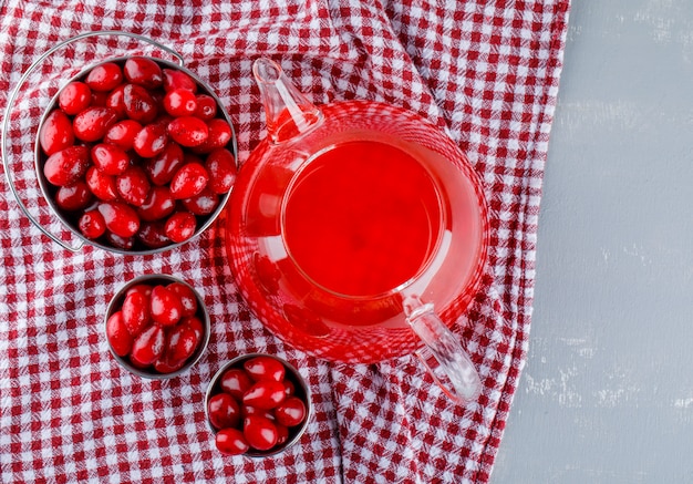 Free photo dogwood berries with drink in mini buckets on plaster and picnic cloth.