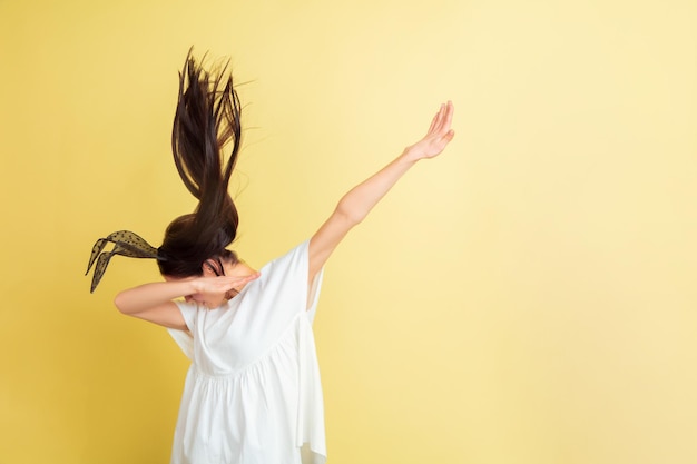 Free photo doing dab, dabbing. caucasian woman as an easter bunny on yellow studio background.