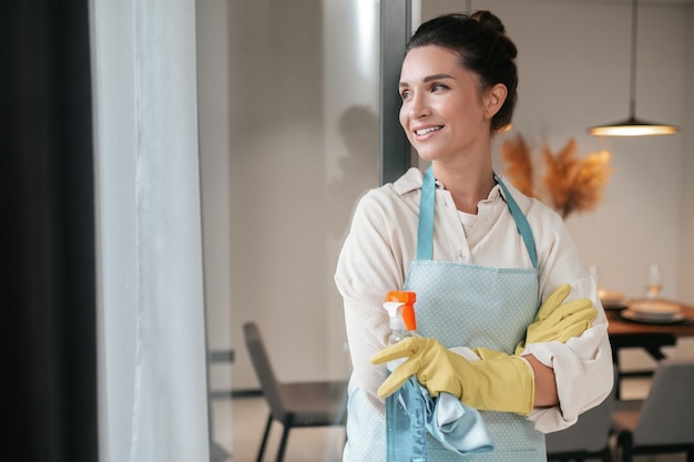 Domestic routine. Smiling housewife in apron standing in the kitchen