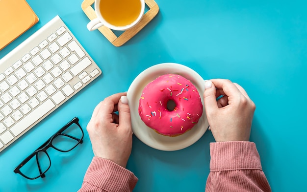 Free photo donut tea and keyboard on a blue background flat lay