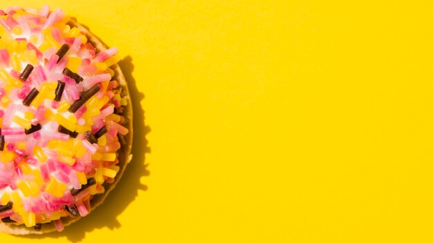 Donut with sprinkles against yellow background