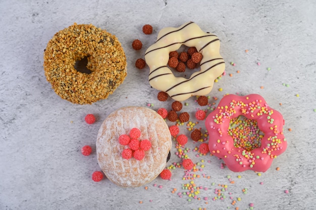 Donuts decorated icing and sprinkles on white surface top view