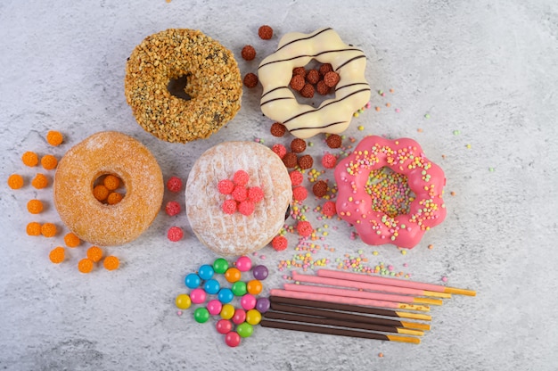 Free photo donuts decorated icing and sprinkles on white surface top view