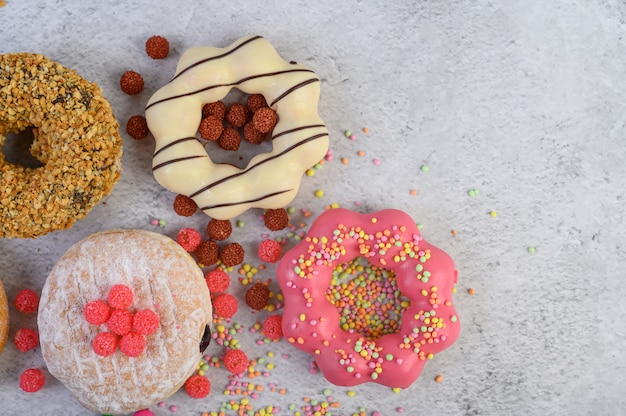 Donuts decorated icing and sprinkles on white surface top view