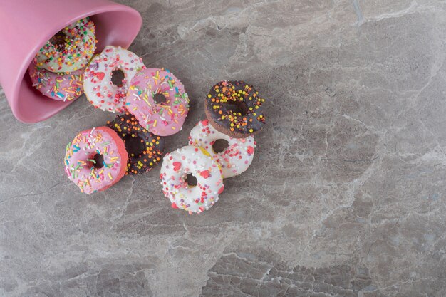 Donuts spilled out of a bowl on marble surface