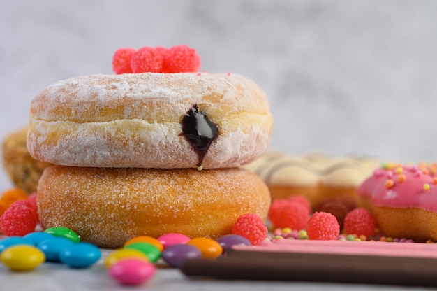 Donuts sprinkled with icing sugar and candy on a white surface.