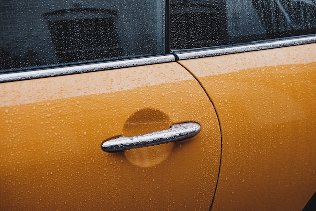 Free photo a door handle of a wet yellow car