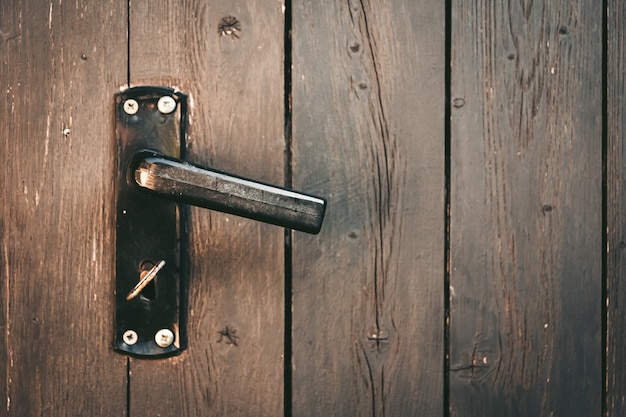 Free Photo door handle with a key on a wooden door