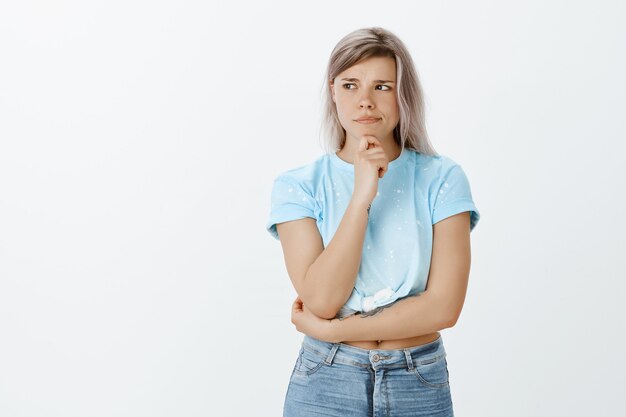 Doubtful blonde girl posing in the studio