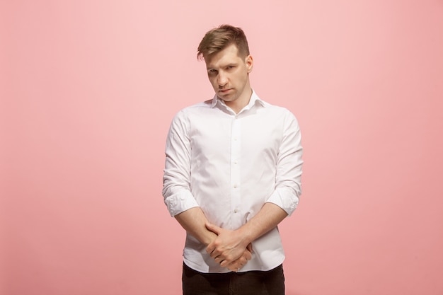 Free photo doubtful pensive man with thoughtful expression making choice against pink wall