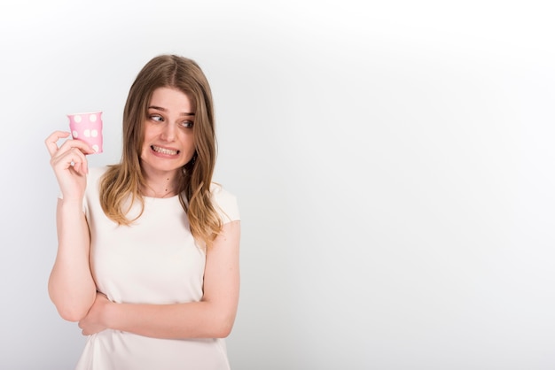 Doubtful young woman with paper cup