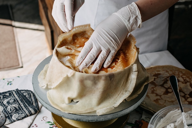 dough inside round pan with cook spreading slices on it inside kitchen