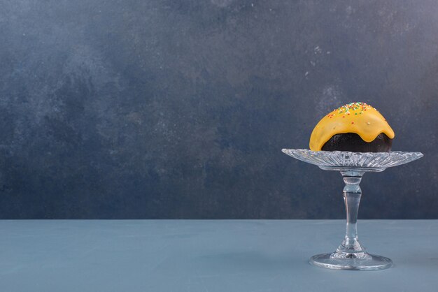 Free photo doughnut on glass plate on marble table .