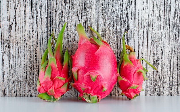 Free Photo dragon fruit on  white and wooden table. side view.