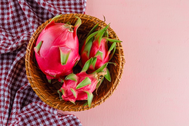 Free Photo dragon fruit in a wicker basket on pink and picnic cloth, flat lay.