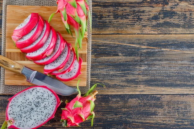 Free Photo dragon fruit with cutting board, knife flat lay on wooden table