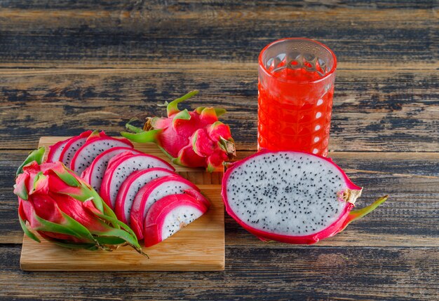 Dragon fruit with juice high angle view on wooden and cutting board