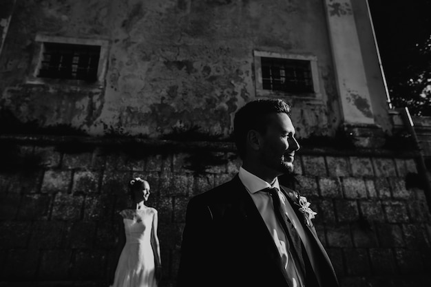 Dramatic black and white picture of wedding couple posing before a stone wall