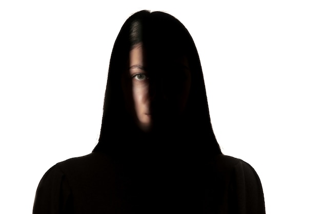 Dramatic portrait of young girl in the dark isolated on white studio wall