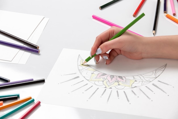 Drawing a young girl hand drawing a moon with green pencil