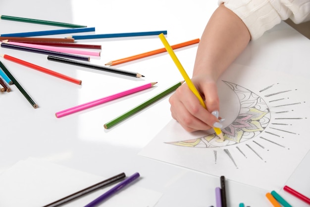 Drawing a young girl hand drawing a moon with yellow pencil