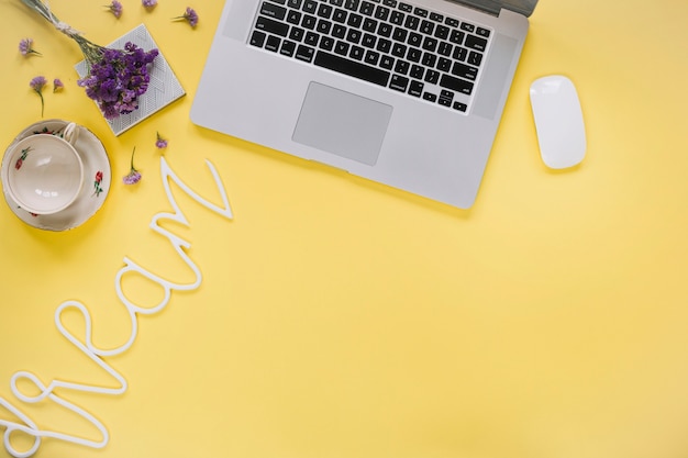 Free photo dream word near laptop and empty cup on yellow surface