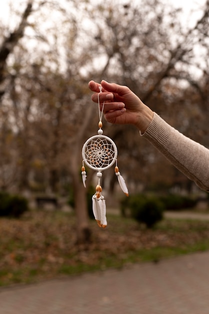 Free Photo dreamcatcher held by hand outdoors