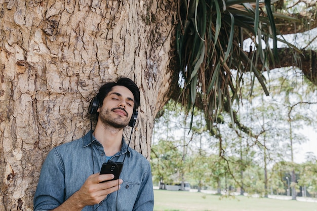 Dreaming man enjoying music in park