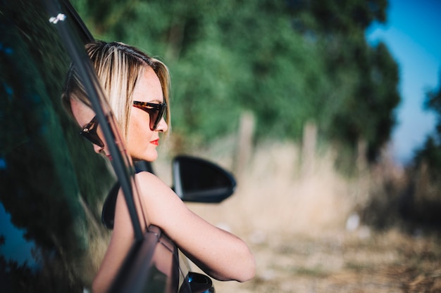 Dreaming woman enjoying views from car window