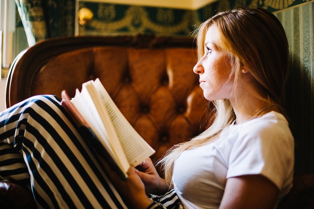 Free photo dreaming woman with book at home