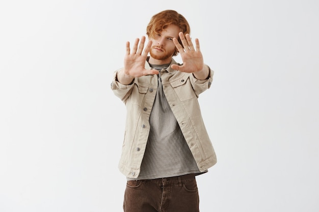 Free photo dreamy bearded redhead guy posing against the white wall