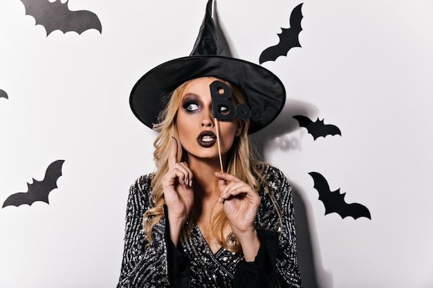 Free Photo dreamy blonde woman posing at halloween party. indoor photo of  elegant vampire girl enjoying carnival.