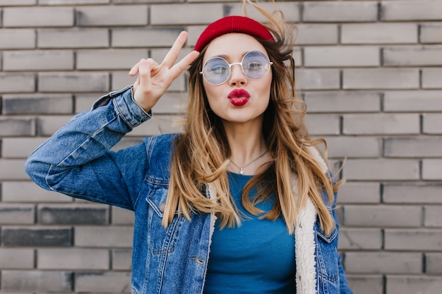 Dreamy caucasian woman in trendy clothes on brick wall