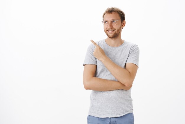 Dreamy and creative ambitious male entrepreneur standing pointing and gazing at upper left corner with pleased happy smile feeling delight and satisfaction enjoying nice view