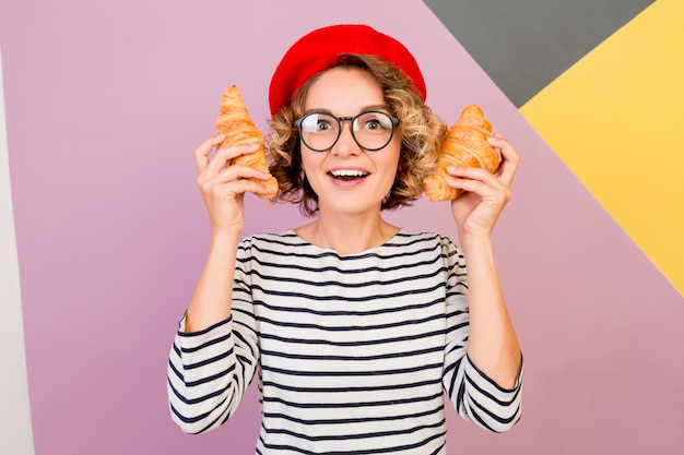 Free Photo dreamy cute lady in red beret  holding big tasty croissants in hands.