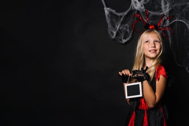 Free photo dreamy girl in halloween costume holding chalkboard