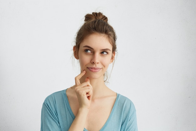 Free Photo dreamy young woman looking thoughtfully aside holding her finger on chin, having ideas or planning something