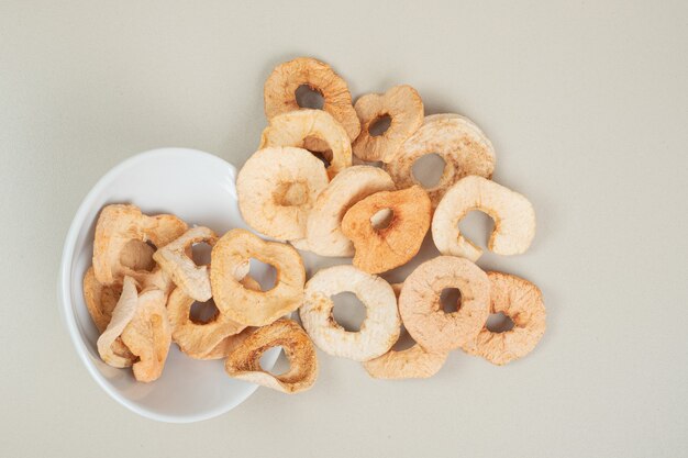 Dried apple chips out of white bowl