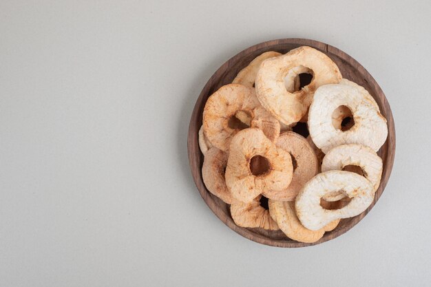 Dried apple chips on wooden plate