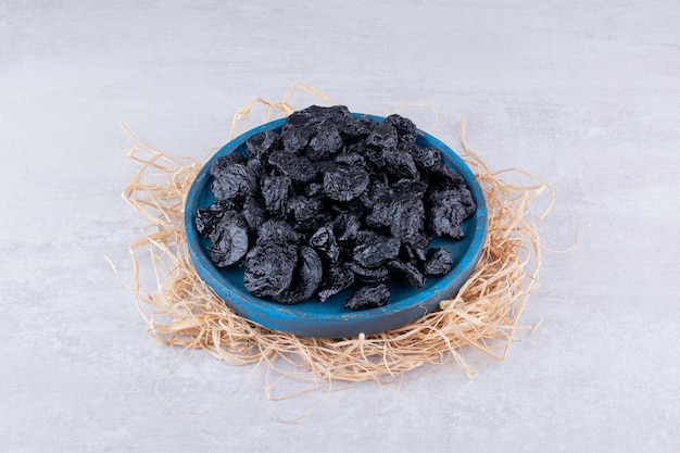 Dried black sultanas in a plate on concrete background. High quality photo