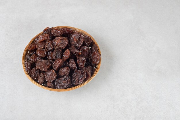 Dried brown plums in a ceramic cup.