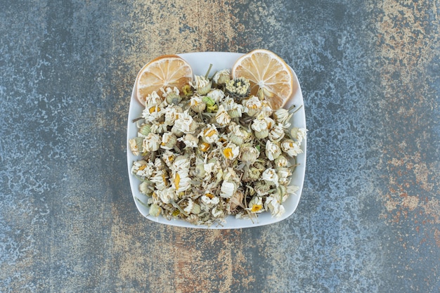 Dried chamomile flower in white bowl.