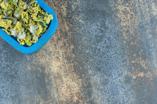 Dried chrysanthemum petals on blue plate.