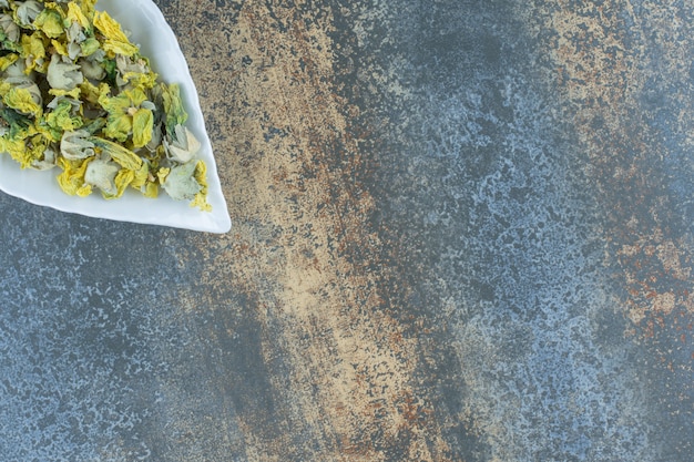 Dried chrysanthemum petals on leaf-shaped plate.