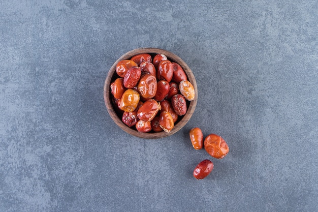 Dried elaeagnus in a wooden bowl, on the marble background.