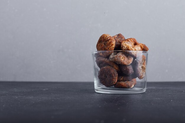 Dried figs in a glass cup on grey background. 