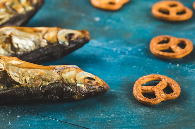 Dried fish snacks on the blue background with pretzel crackers